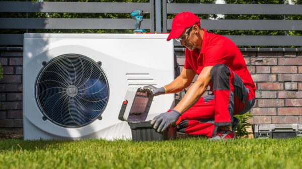 Professional Caucasian Heat Pumps Technician in His 40s Installing New Residential Modern Heating Device. HVAC Industry Theme.