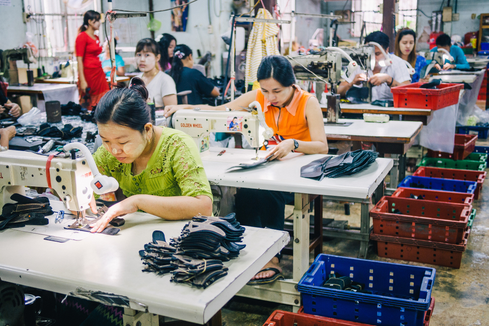 Burmese Female Migrant in Myanmar Workers Sewing or Stitching Leather Shoes in footwear production line of factory in Sankhlaburi, Kanchanaburi, Thai-Burma border