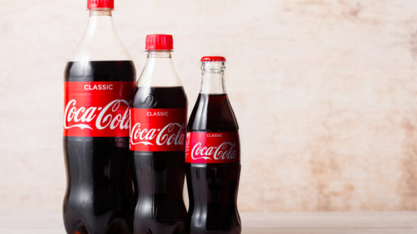 lastic and glass bottles of Original Coca-Cola soft drink on wood. Most popular drink in the world.