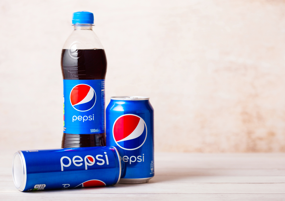 Plastic bottle and aluminium cans of PepsiCo Cola soft drink on wood.American multinational food and beverage company