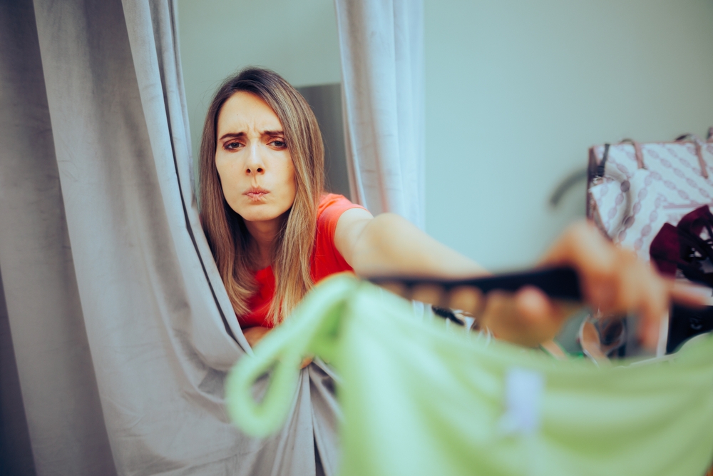 Unhappy Fashion Store Client returns Ill-fitting Garment. Displeased customer trying on a bathing suit not fitting well