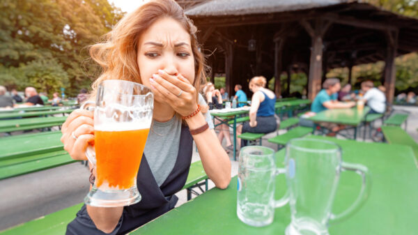 A girl tries a beer with an expression of disgust in a street bar. Concept of alcohol poisoning and quit drinking