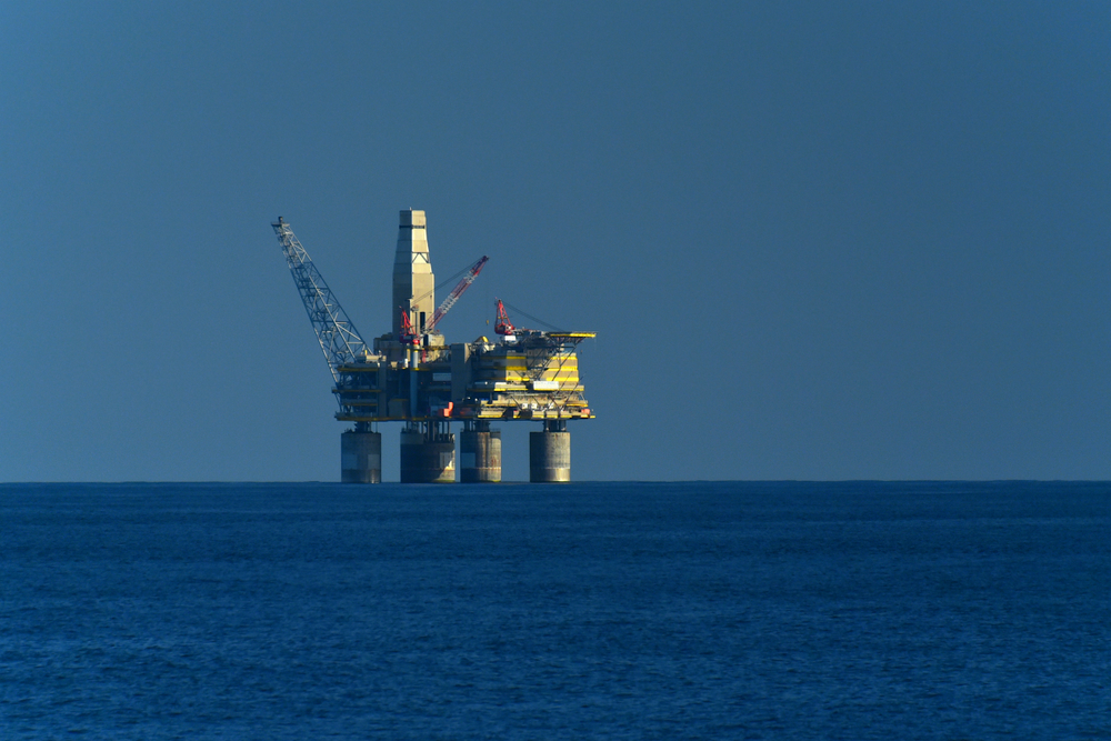 Drilling platform in the ocean. High yellow construction on deep blue water. Mining of oil and gas. The process of drilling a well. deep-sea mining