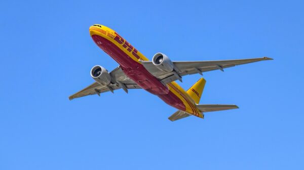 DHL Airplane flying in clear blue sky.