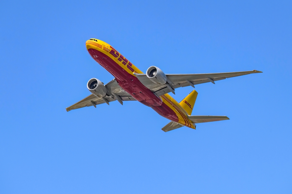 DHL Airplane flying in clear blue sky.