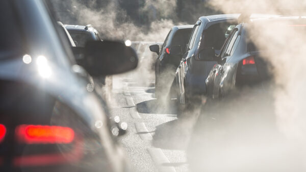 Blurred silhouettes of cars surrounded by steam from the exhaust pipes. Traffic jam Euro 7