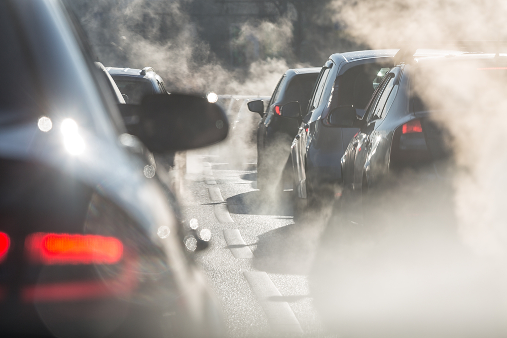 Blurred silhouettes of cars surrounded by steam from the exhaust pipes. Traffic jam Euro 7