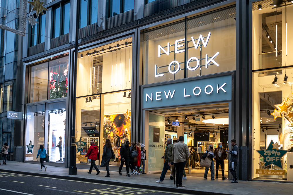 New Look big new clothes retail modern city centre store shop with brand logo and sign illuminated at night busy with tourists and shoppers