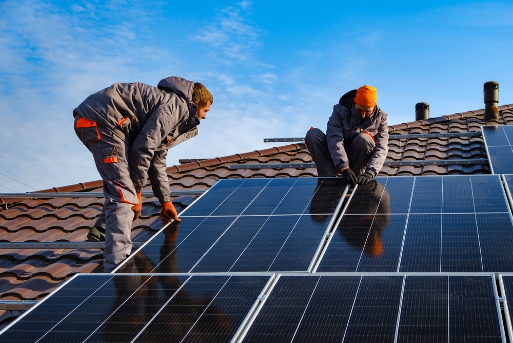 Installing a Solar Cell on a Roof. Solar panels on roof. Workers installing solar cell farm power plant eco technology. One in five homeowners can’t afford to make green home improvements, according to new data from Lloyds Banking Group.