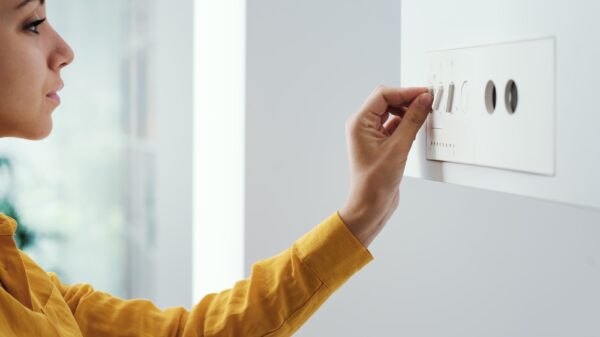 Young woman checking settings and temperature on the boiler at home. The government is set to ban fossil fuel heating such as hydrogen-ready boilers based on its consultation on low-carbon building standards.