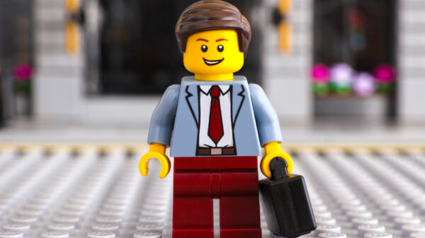 Lego businessman with suitcase stay on the street. Studio shot.