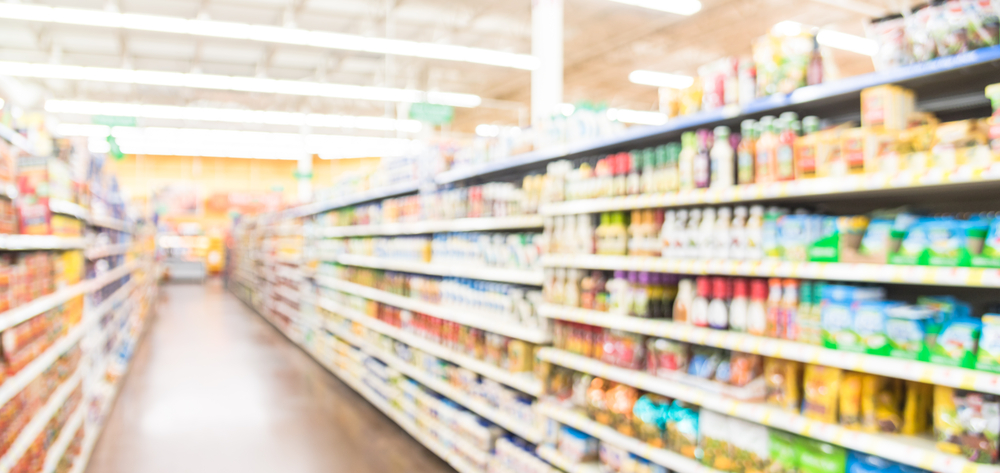 Blurred selection of pasta, ketchup, condiment, tomato sauce and canned vegetable on shelves in a supermarket