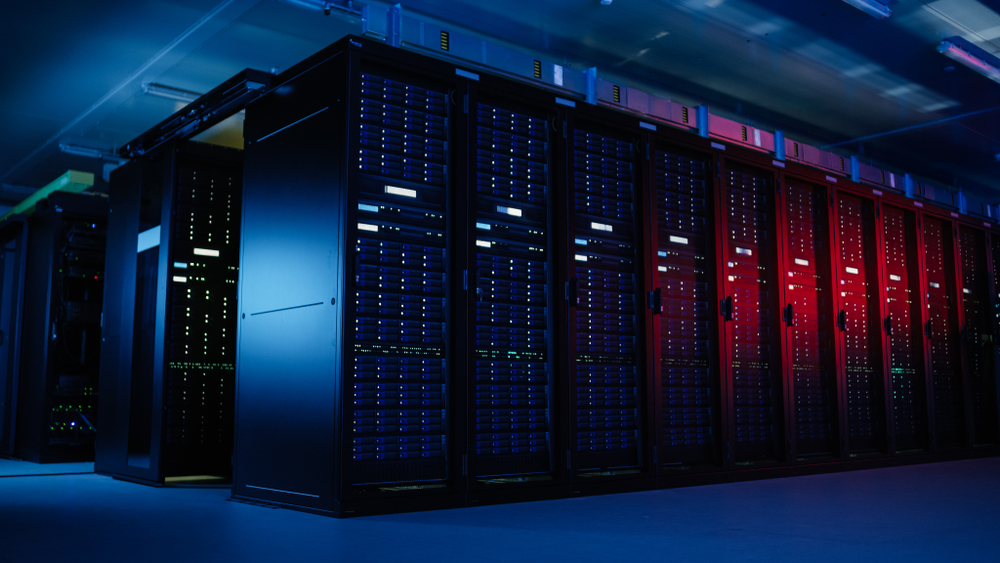 Shot of Data Centre With Multiple Rows of Fully Operational Server Racks. Modern Telecommunications, Artificial Intelligence, Supercomputer Technology Concept. Shot in Dark with Neon Blue, Pink Lights