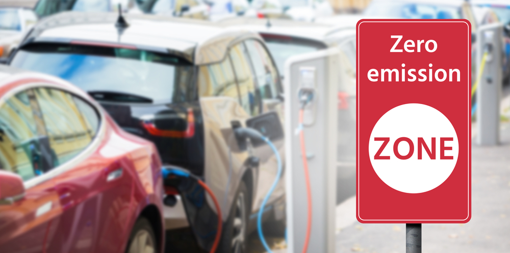 Road sign "Zero emission ZONE" on a background of electric cars. Clean mobility concept