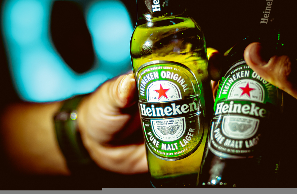 Photograph of two men toasting with two bottles of heineken beer.