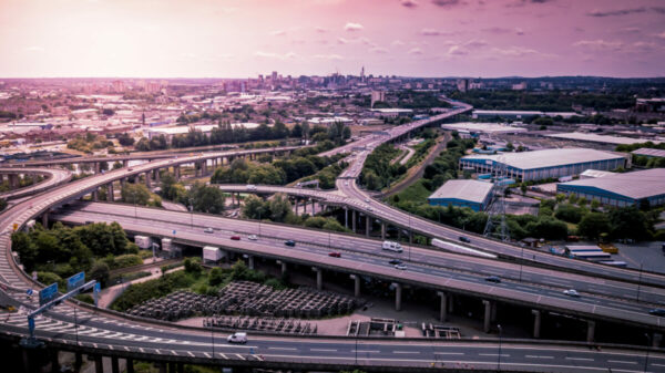 Motorway complex road junction aerial view with traffic moving in the UK. Cars, lorries, vans and a train can be seen travelling through a busy road interchange from above. infrastructure