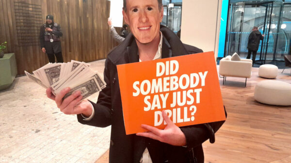 Extinction Rebellion protester holding a poster saying "did somebody say just drill" and oil money.A team of Extinction Rebellion activists have infiltrated the London HQ of McCann Worldgroup, in protest at the company’s link with oil firm Saudi Aramco.
