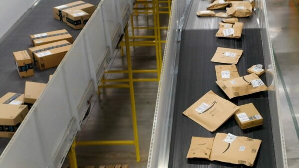 Amazon is using a new AI model to help determine the most efficient type of packaging for each item, in an effort to speed up the process of meeting its sustainability goals. Image shows Amazon parcels on a conveyor belt.